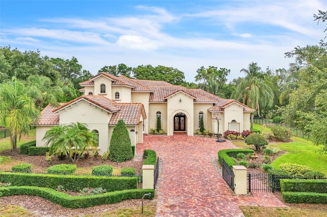 9729 Lake Hugh Dr, Gotha, FL 34734 - mediterranean / spanish home featuring a fenced front yard, decorative driveway, a gate, and stucco siding