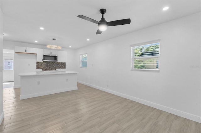 7701 Cassino Ave, Orlando, FL 32819 - kitchen featuring stainless steel microwave, baseboards, recessed lighting, light countertops, and white cabinetry
