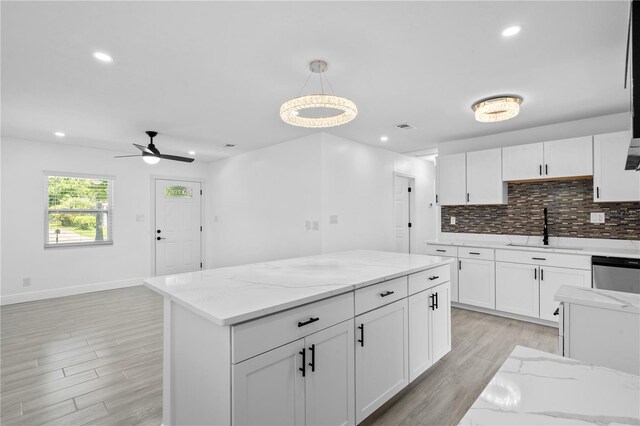 7701 Cassino Ave, Orlando, FL 32819 - kitchen featuring a sink, light wood-style flooring, white cabinetry, recessed lighting, and backsplash