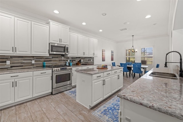 5365 Bowman Dr, Winter Garden, FL 34787 - kitchen featuring stainless steel appliances, a sink, tasteful backsplash, a center island, and white cabinetry