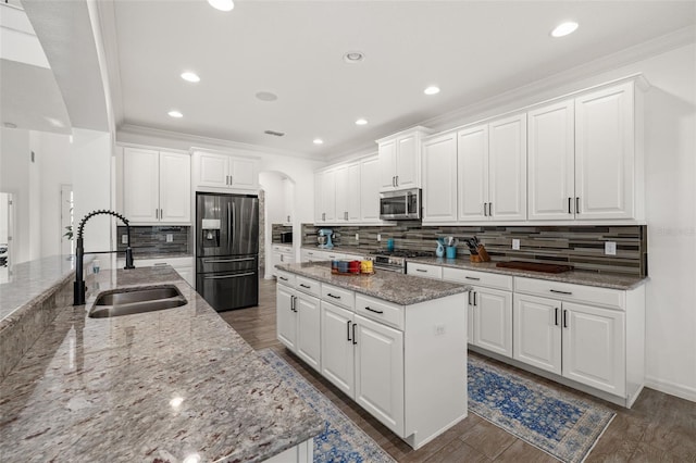 5365 Bowman Dr, Winter Garden, FL 34787 - kitchen featuring stainless steel appliances, a sink, arched walkways, a kitchen island, and backsplash