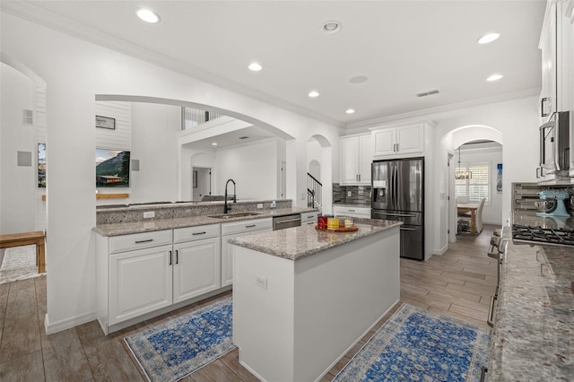 5365 Bowman Dr, Winter Garden, FL 34787 - kitchen featuring stainless steel appliances, a sink, a kitchen island, white cabinetry, and light stone countertops