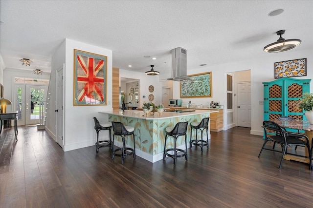 1550 Bluewater Run, Chuluota, FL 32766 - kitchen featuring island range hood, a kitchen breakfast bar, a textured ceiling, dark wood-style flooring, and light countertops