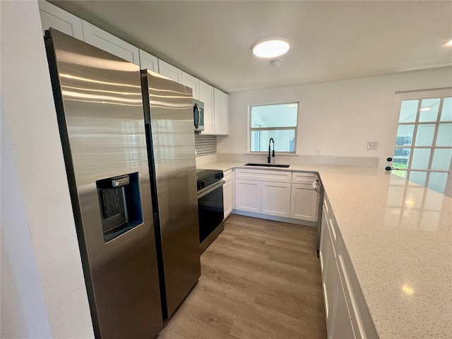 804 Starke Lake Cir, Ocoee, FL 34761 - kitchen with appliances with stainless steel finishes, a sink, white cabinets, light wood-style floors, and decorative backsplash