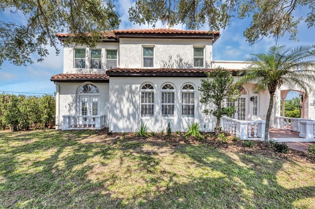 802 S 10th St, Haines City, FL 33844 - mediterranean / spanish home with french doors, a tiled roof, stucco siding, and a front lawn