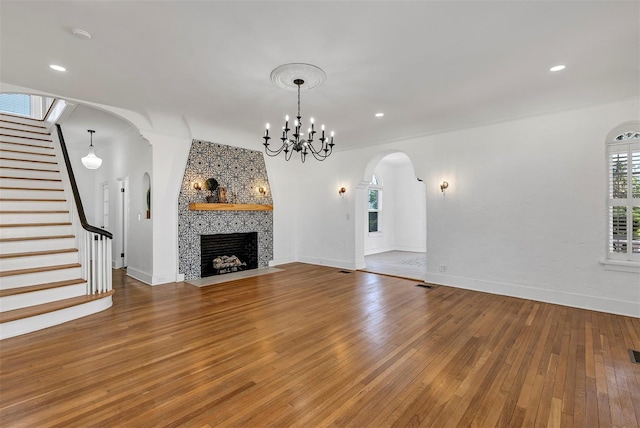 802 S 10th St, Haines City, FL 33844 - unfurnished living room featuring arched walkways, stairs, hardwood / wood-style flooring, baseboards, and a chandelier