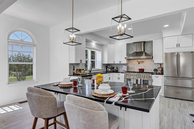 802 S 10th St, Haines City, FL 33844 - kitchen with wall chimney range hood, stainless steel appliances, a chandelier, dark countertops, and recessed lighting