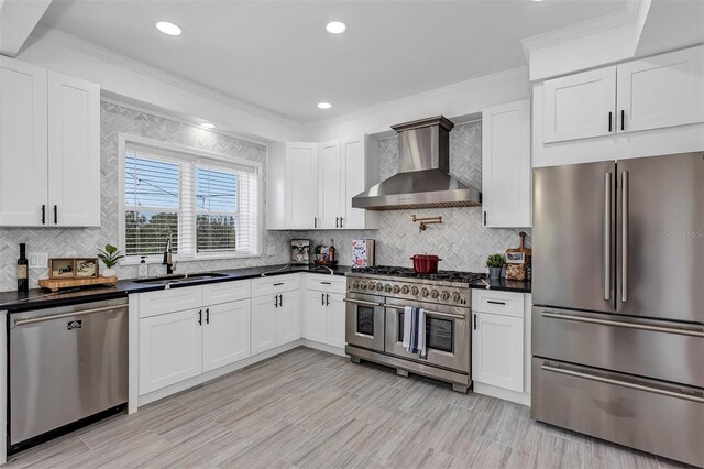 802 S 10th St, Haines City, FL 33844 - kitchen with stainless steel appliances, wall chimney exhaust hood, a sink, dark countertops, and ornamental molding