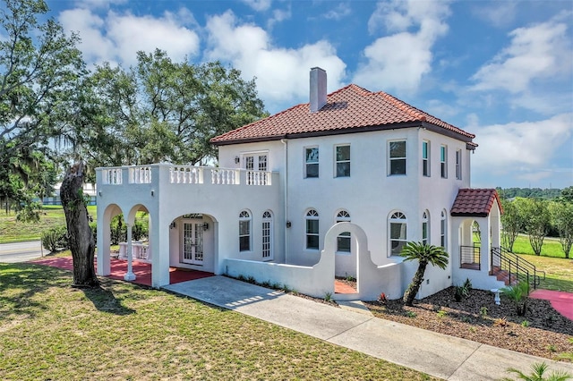 802 S 10th St, Haines City, FL 33844 - view of front of house with french doors, a tiled roof, a chimney, a front yard, and stucco siding