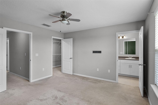 228 Primrose Dr, Davenport, FL 33837 - unfurnished bedroom with a sink, light carpet, a spacious closet, a textured ceiling, and baseboards