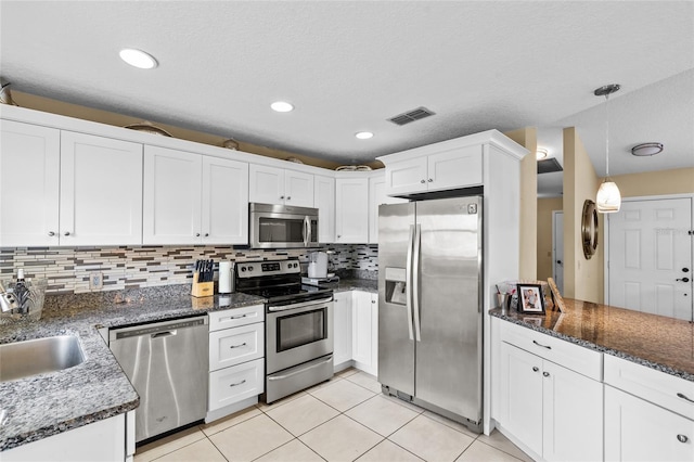 109 Coral Reef Ct N, Palm Coast, FL 32137 - kitchen featuring appliances with stainless steel finishes, white cabinets, light tile patterned floors, tasteful backsplash, and hanging light fixtures
