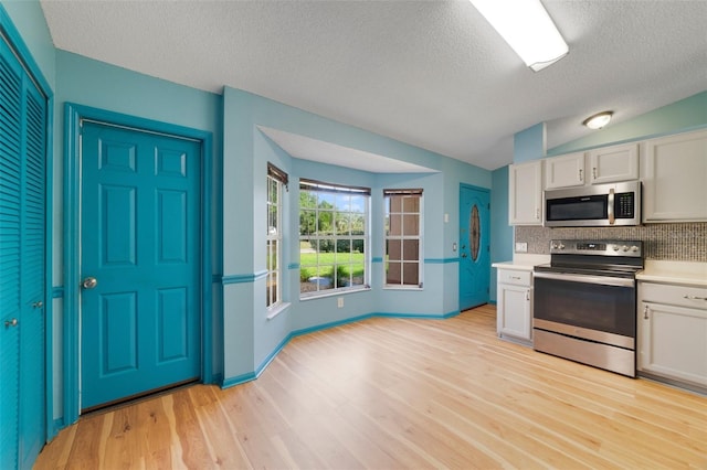 925 S Dean Cir, Deltona, FL 32738 - kitchen featuring appliances with stainless steel finishes, light countertops, backsplash, light wood-type flooring, and white cabinets