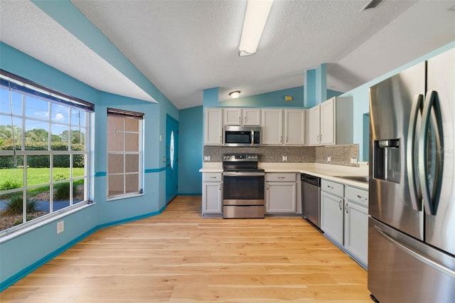 925 S Dean Cir, Deltona, FL 32738 - kitchen featuring stainless steel appliances, vaulted ceiling, light countertops, decorative backsplash, and light wood-type flooring