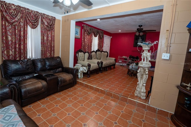 living area with a ceiling fan and concrete block wall