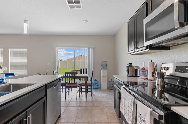 601 Watusi Way, Saint Cloud, FL 34772 - kitchen with appliances with stainless steel finishes, light countertops, hanging light fixtures, light tile patterned floors, and dark cabinetry