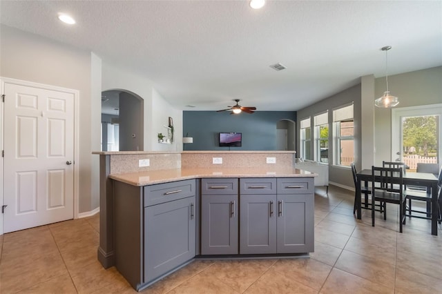 3223 Blazing Star Ln, Harmony, FL 34773 - kitchen featuring arched walkways, gray cabinets, backsplash, a ceiling fan, and hanging light fixtures
