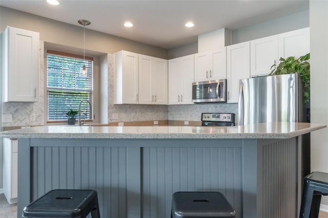 3223 Blazing Star Ln, Harmony, FL 34773 - kitchen featuring appliances with stainless steel finishes, white cabinets, a kitchen bar, tasteful backsplash, and recessed lighting