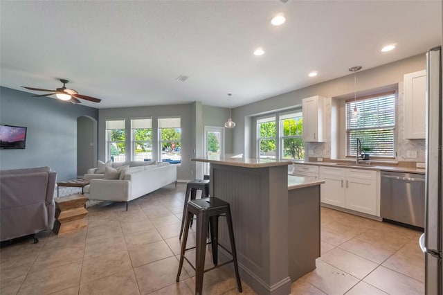 3223 Blazing Star Ln, Harmony, FL 34773 - kitchen featuring dishwasher, a sink, open floor plan, white cabinets, and healthy amount of natural light