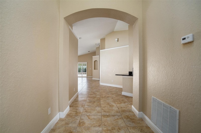 2830 Alton Dr, Kissimmee, FL 34741 - hall with arched walkways, a textured wall, lofted ceiling, and baseboards