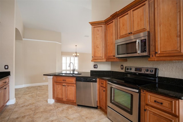 2830 Alton Dr, Kissimmee, FL 34741 - kitchen featuring appliances with stainless steel finishes, a sink, a peninsula, brown cabinets, and a chandelier