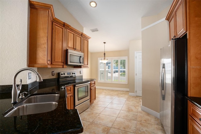 2830 Alton Dr, Kissimmee, FL 34741 - kitchen with stainless steel appliances, a sink, brown cabinets, pendant lighting, and dark stone counters
