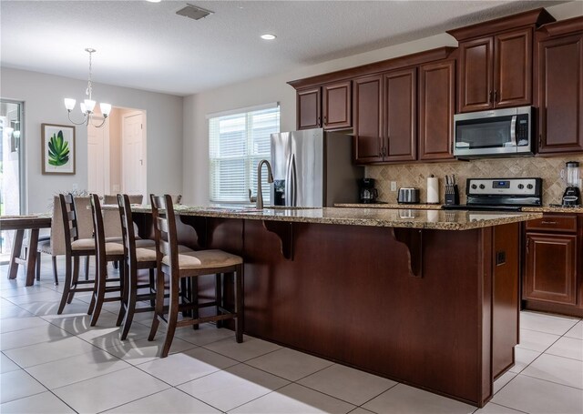 1836 Sandy Park Trl, Kissimmee, FL 34747 - kitchen featuring appliances with stainless steel finishes, a kitchen bar, backsplash, light stone counters, and a sink