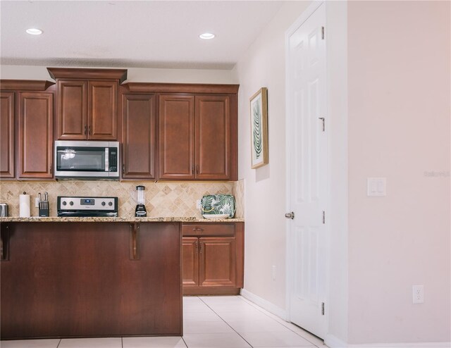 1836 Sandy Park Trl, Kissimmee, FL 34747 - kitchen featuring appliances with stainless steel finishes, light tile patterned floors, backsplash, light stone countertops, and baseboards