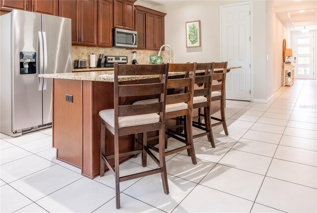 1836 Sandy Park Trl, Kissimmee, FL 34747 - kitchen with appliances with stainless steel finishes, light tile patterned flooring, tasteful backsplash, a center island with sink, and a breakfast bar