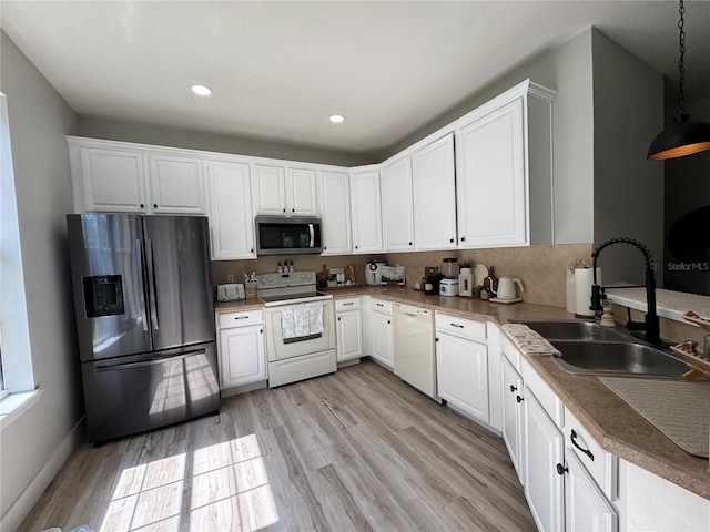 7544 Red Mill Cir, New Port Richey, FL 34653 - kitchen with appliances with stainless steel finishes, a sink, white cabinetry, light wood-style floors, and hanging light fixtures
