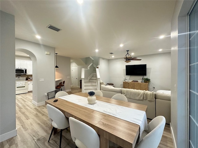7544 Red Mill Cir, New Port Richey, FL 34653 - dining area with stairs, a ceiling fan, light wood finished floors, arched walkways, and baseboards