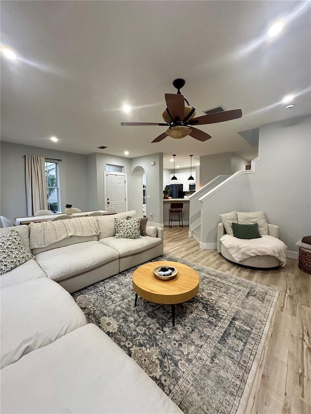 7544 Red Mill Cir, New Port Richey, FL 34653 - living area featuring a ceiling fan, light wood finished floors, arched walkways, stairway, and baseboards