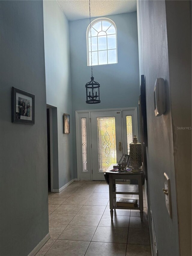 4186 Buglers Rest Pl, Casselberry, FL 32707 - foyer with a high ceiling, baseboards, tile patterned floors, a textured ceiling, and a chandelier