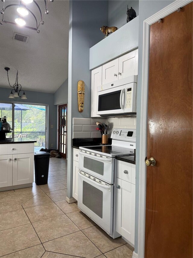 4186 Buglers Rest Pl, Casselberry, FL 32707 - kitchen featuring white appliances, dark countertops, light tile patterned floors, white cabinetry, and vaulted ceiling