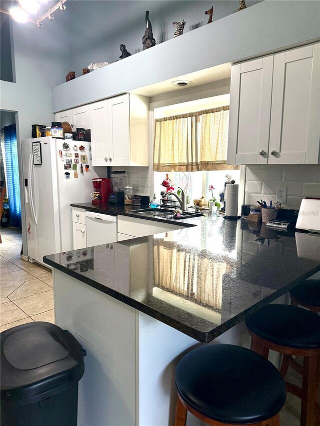 4186 Buglers Rest Pl, Casselberry, FL 32707 - kitchen featuring white appliances, a peninsula, white cabinetry, a kitchen breakfast bar, and a sink