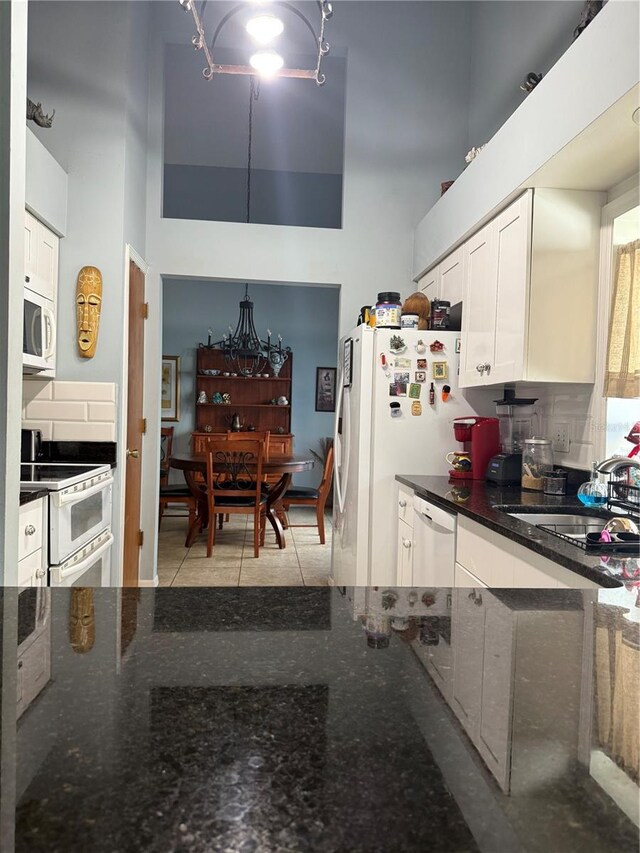 4186 Buglers Rest Pl, Casselberry, FL 32707 - kitchen with white appliances, white cabinets, a sink, dark stone countertops, and a towering ceiling