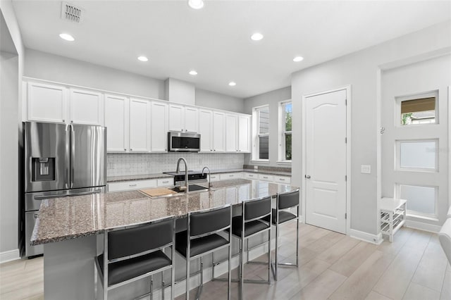 14126 Walcott Ave, Orlando, FL 32827 - kitchen featuring appliances with stainless steel finishes, decorative backsplash, white cabinetry, an island with sink, and a sink