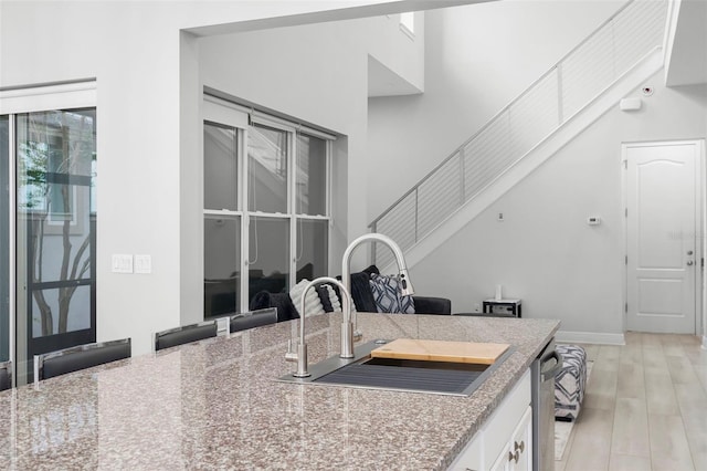 14126 Walcott Ave, Orlando, FL 32827 - kitchen with a sink, white cabinetry, light wood-style floors, dishwasher, and a towering ceiling