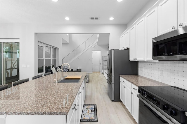 14126 Walcott Ave, Orlando, FL 32827 - kitchen featuring appliances with stainless steel finishes, a sink, a center island with sink, white cabinetry, and stone countertops