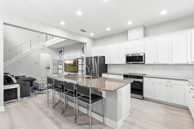14126 Walcott Ave, Orlando, FL 32827 - kitchen featuring appliances with stainless steel finishes, a sink, a breakfast bar, light wood finished floors, and an island with sink