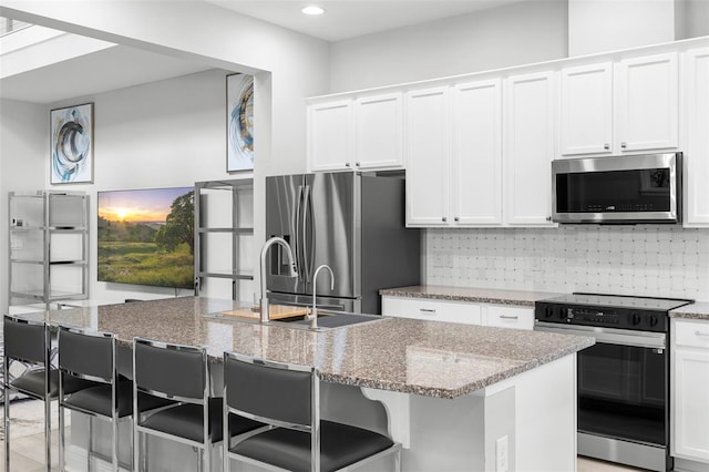 14126 Walcott Ave, Orlando, FL 32827 - kitchen with stainless steel appliances, white cabinets, light stone counters, a center island with sink, and recessed lighting