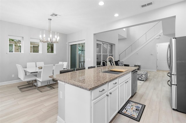 14126 Walcott Ave, Orlando, FL 32827 - kitchen with stainless steel appliances, a sink, a chandelier, light stone countertops, and white cabinetry