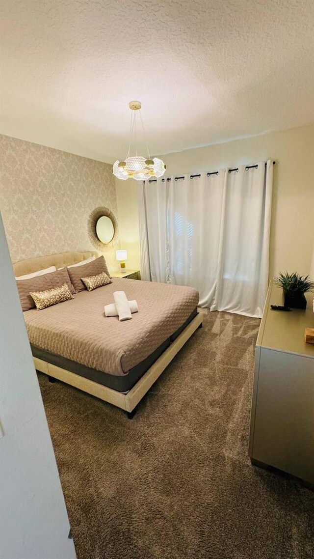 851 Drop Shot Dr, Davenport, FL 33896 - bedroom featuring dark carpet, wallpapered walls, a chandelier, and a textured ceiling