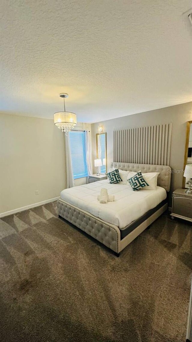 851 Drop Shot Dr, Davenport, FL 33896 - bedroom with dark colored carpet, a textured ceiling, baseboards, and a chandelier
