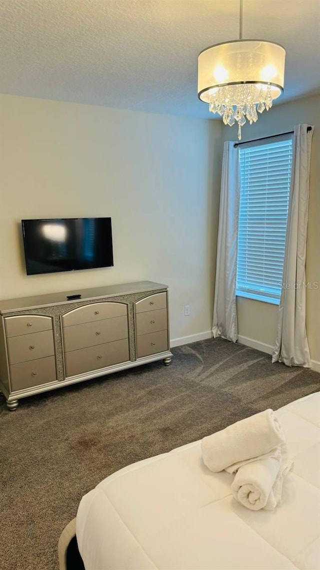 851 Drop Shot Dr, Davenport, FL 33896 - bedroom featuring dark carpet, a chandelier, baseboards, and a textured ceiling