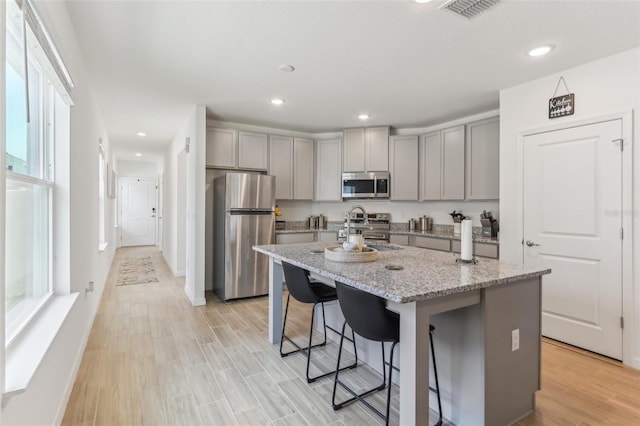 4122 Sagefield Dr, Saint Cloud, FL 34773 - kitchen with stainless steel appliances, gray cabinets, light stone countertops, a kitchen island with sink, and recessed lighting