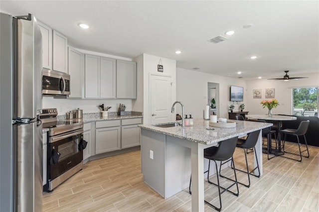 4122 Sagefield Dr, Saint Cloud, FL 34773 - kitchen with appliances with stainless steel finishes, gray cabinets, a sink, a breakfast bar area, and an island with sink