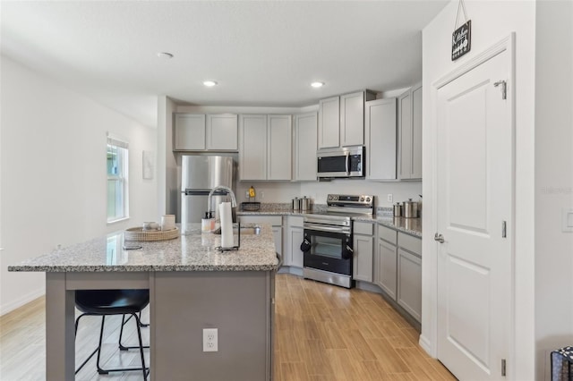 4122 Sagefield Dr, Saint Cloud, FL 34773 - kitchen with appliances with stainless steel finishes, gray cabinets, a sink, light stone countertops, and a breakfast bar area