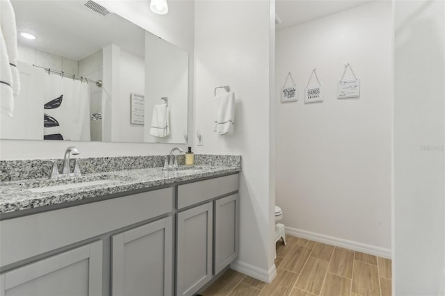 4122 Sagefield Dr, Saint Cloud, FL 34773 - bathroom featuring toilet, double vanity, baseboards, wood finish floors, and a shower with shower curtain