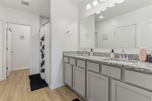 4122 Sagefield Dr, Saint Cloud, FL 34773 - bathroom featuring double vanity, wood tiled floors, baseboards, and a shower with shower curtain