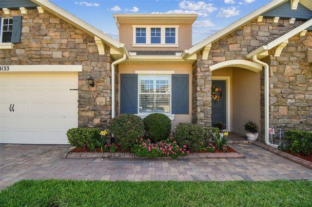 4133 Foxhound Dr, Clermont, FL 34711 - view of exterior entry featuring stone siding, stucco siding, and a garage
